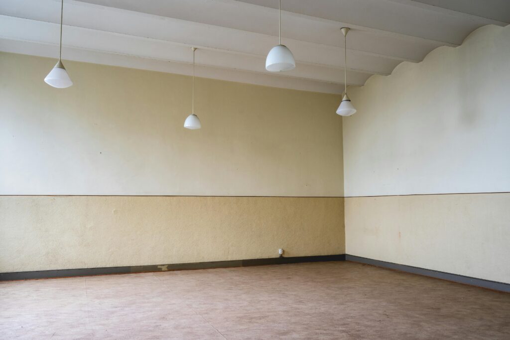Spacious empty room with hanging lamps and parquet flooring, perfect for interior design concepts.