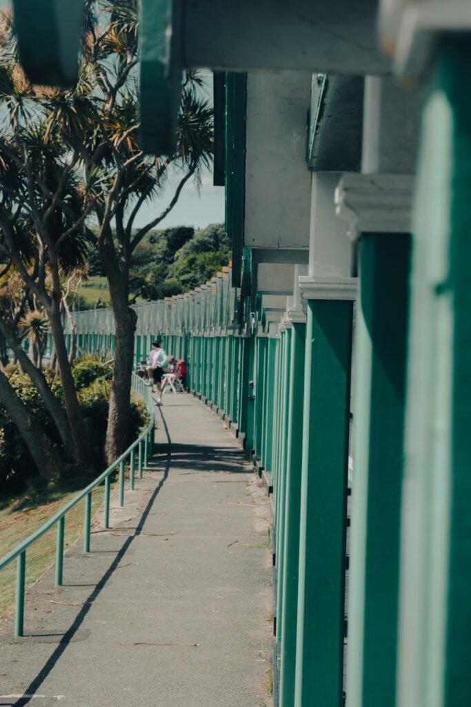 A tranquil urban walkway lined with green columns, perfect for a summer's day stroll.