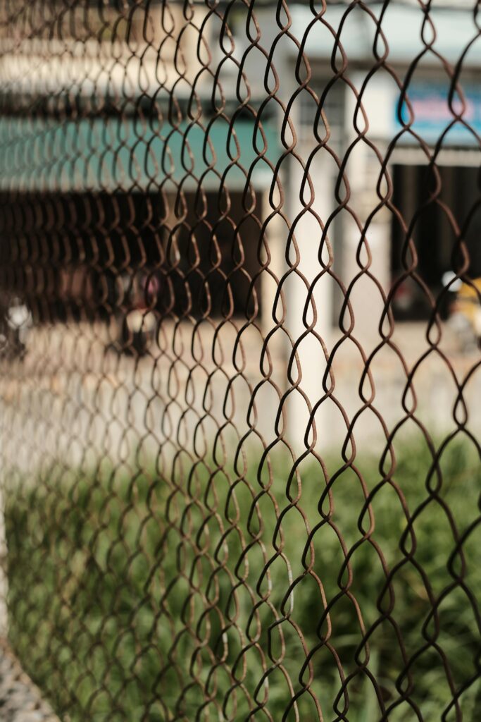 Detailed shot of a chain link fence with blurred urban background, indicating enclosure and protection.