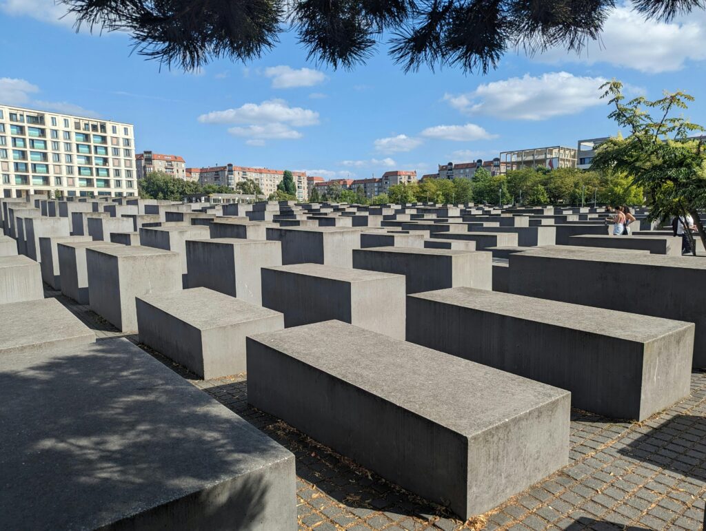 View of the Holocaust Memorial in Berlin under a clear blue sky.