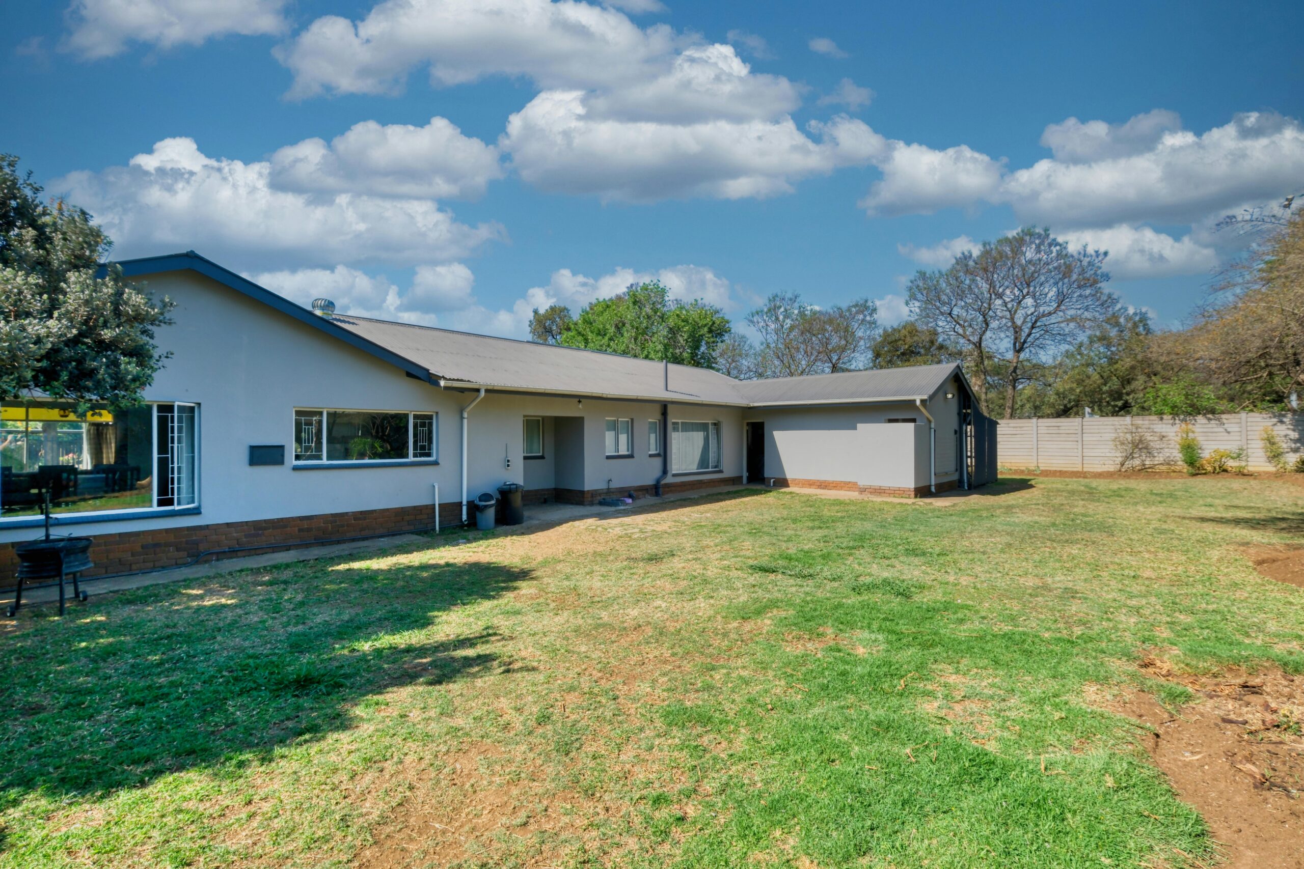 A modern suburban house with a spacious backyard under a clear blue sky, perfect for lifestyle imagery.